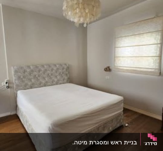 מיטה עם מזרן לבן בחדר שינה